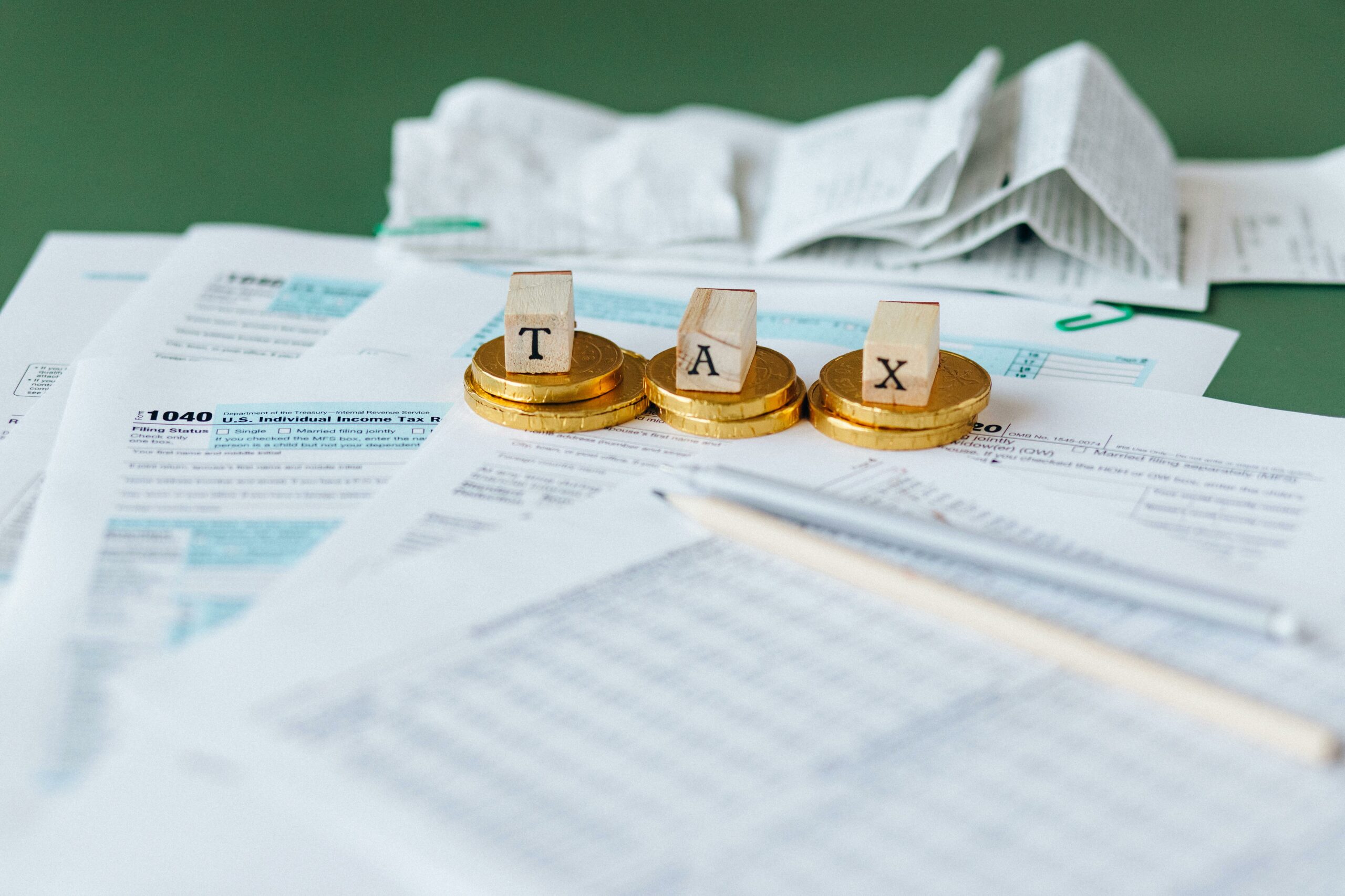 TAX word above a pile of disorganized tax forms illustrating the complexity of anything related to tax