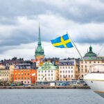 Photo of Stockholm's Old Town, view from the bay with a boat and the Swedish flag, Sweden