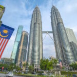 Malaysian Flag with the Petronas Towers and various buildings in the background in Kuala Lumpur, capital of Malaysia